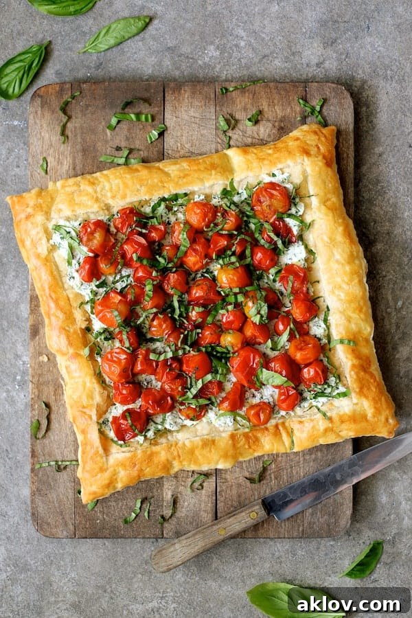 Photo of an unsliced Roasted Cherry Tomato Tart with Herbed Ricotta on a wooden cutting board, showcasing its perfectly golden crust and colorful toppings.
