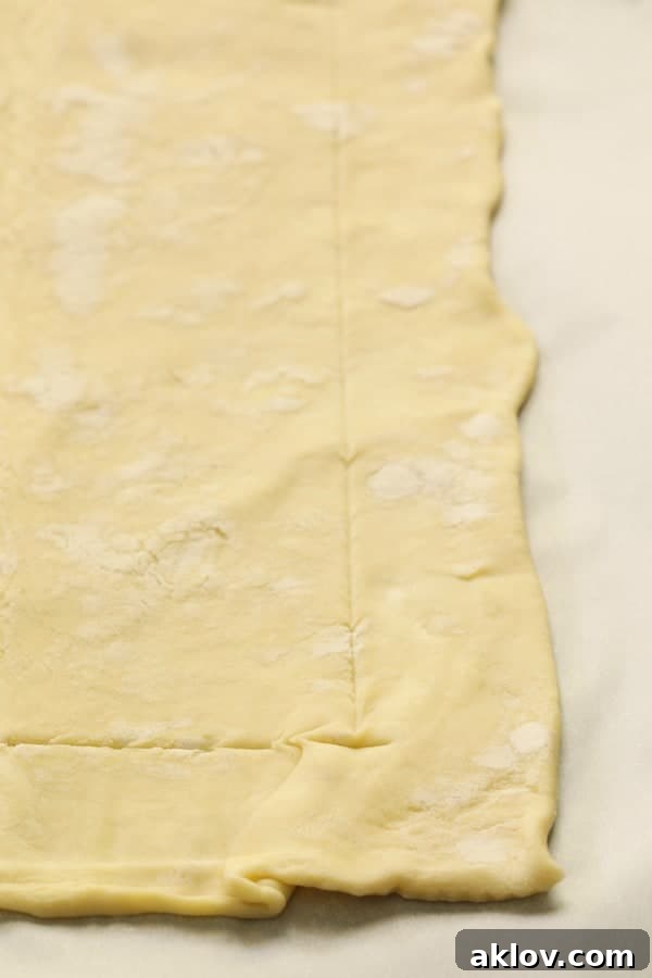Close-up photo showing how to gently score puff pastry crust with a knife before baking, creating a border.