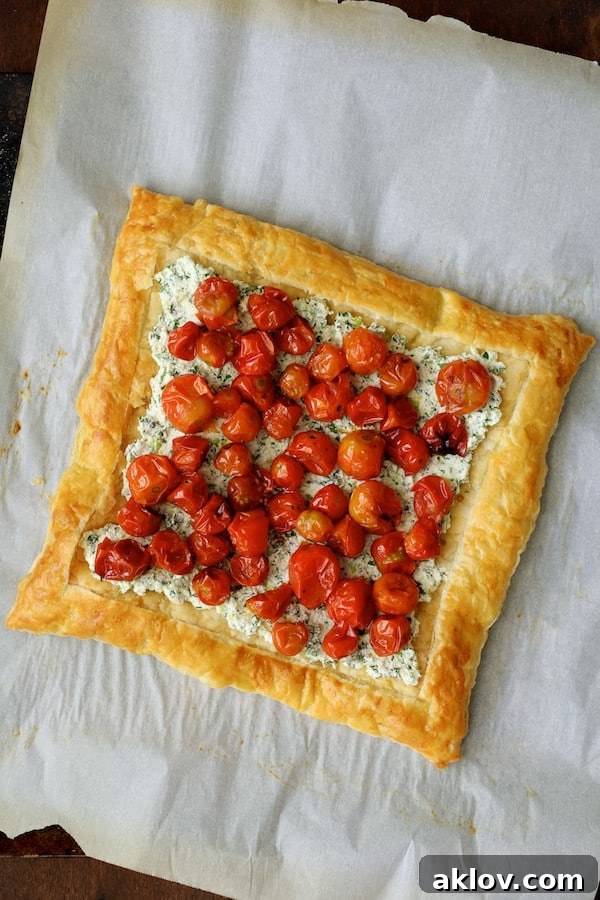 Photo of the tart with roasted cherry tomatoes carefully placed on top of the herbed ricotta mixture.