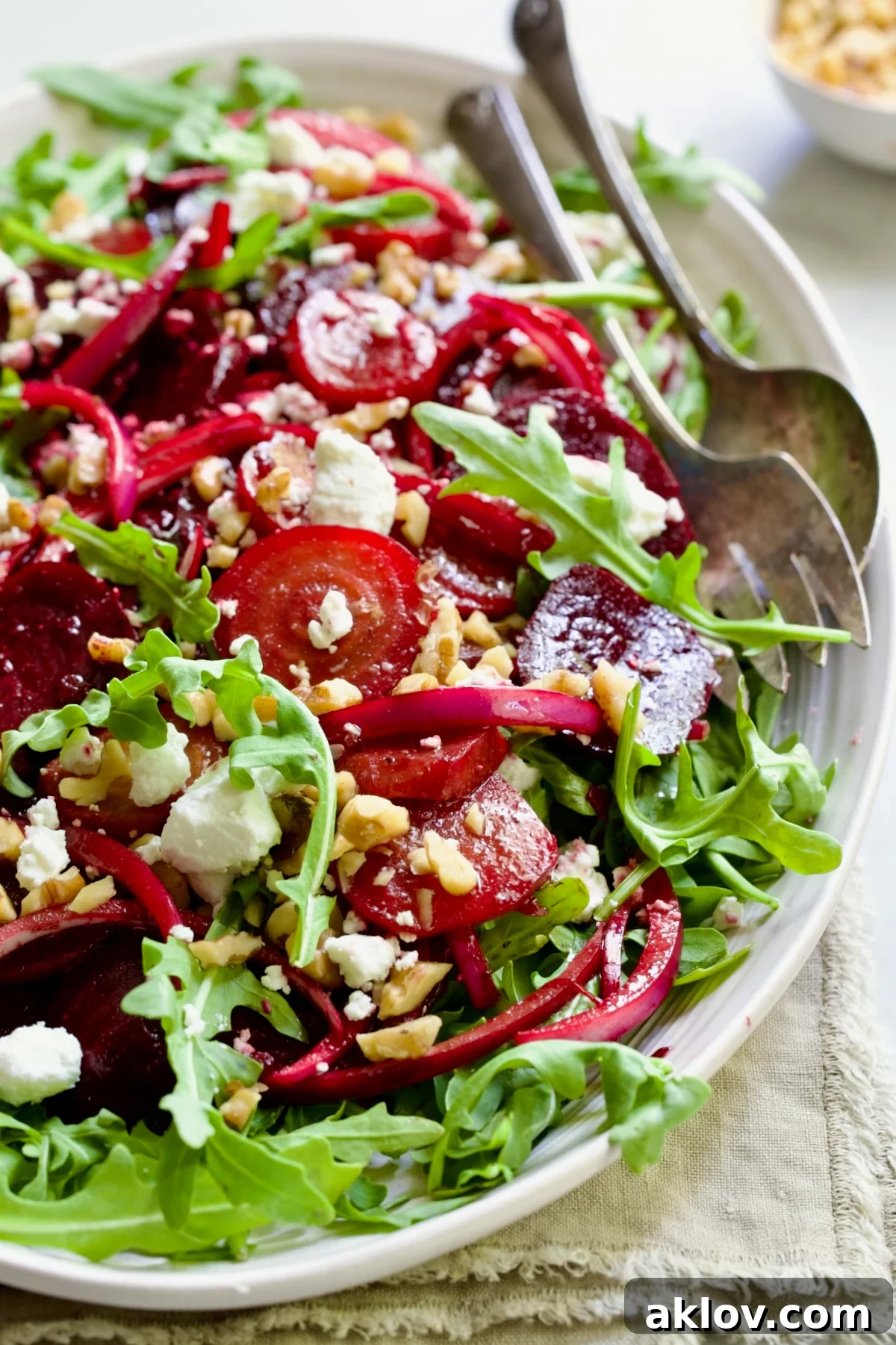Roasted Beet Salad on oval white platter with serving utensils.