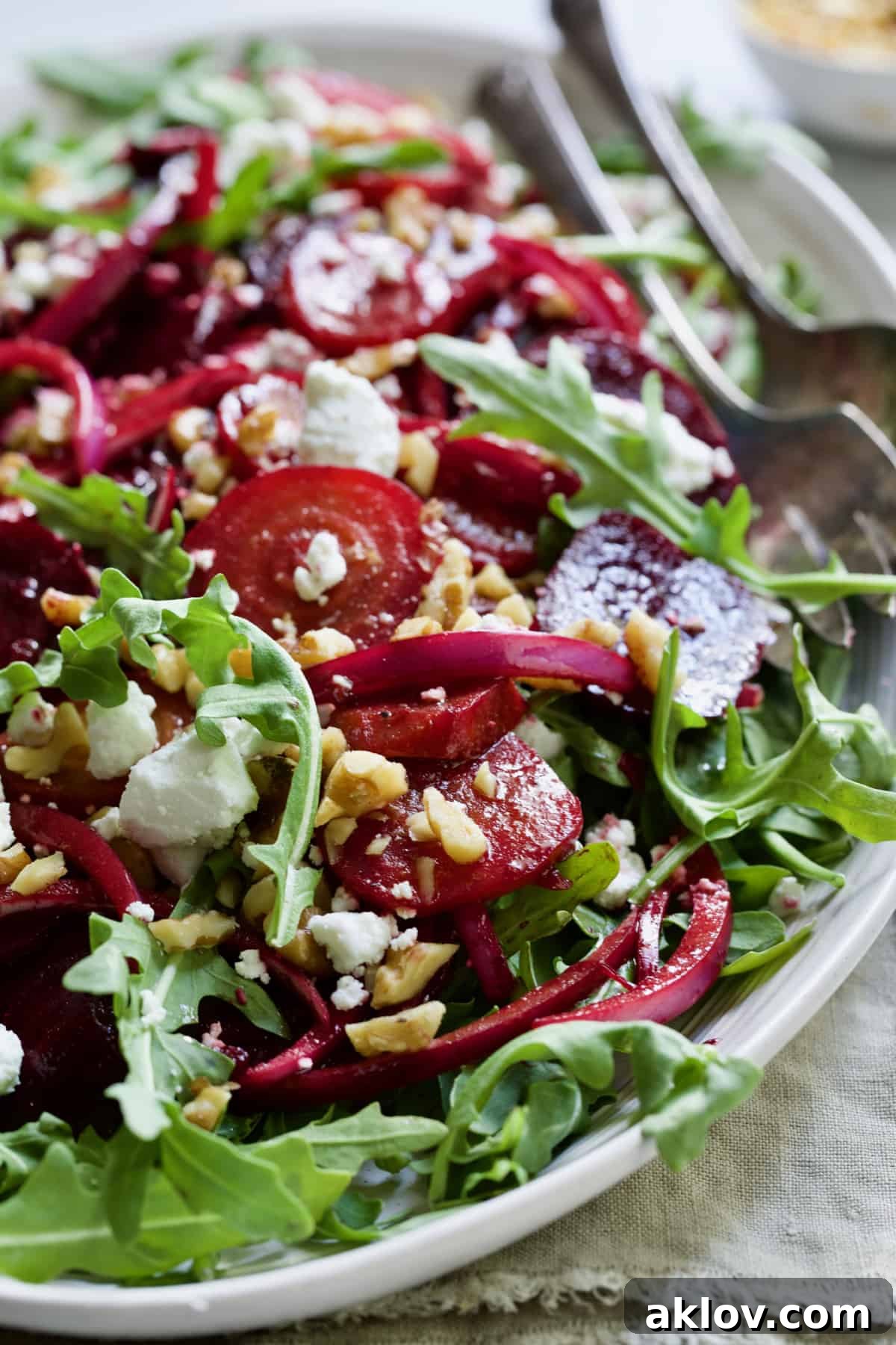 Roasted Beet Salad with Walnuts Goat Cheese and Honey Balsamic Dressing on white platter with beige napkin.