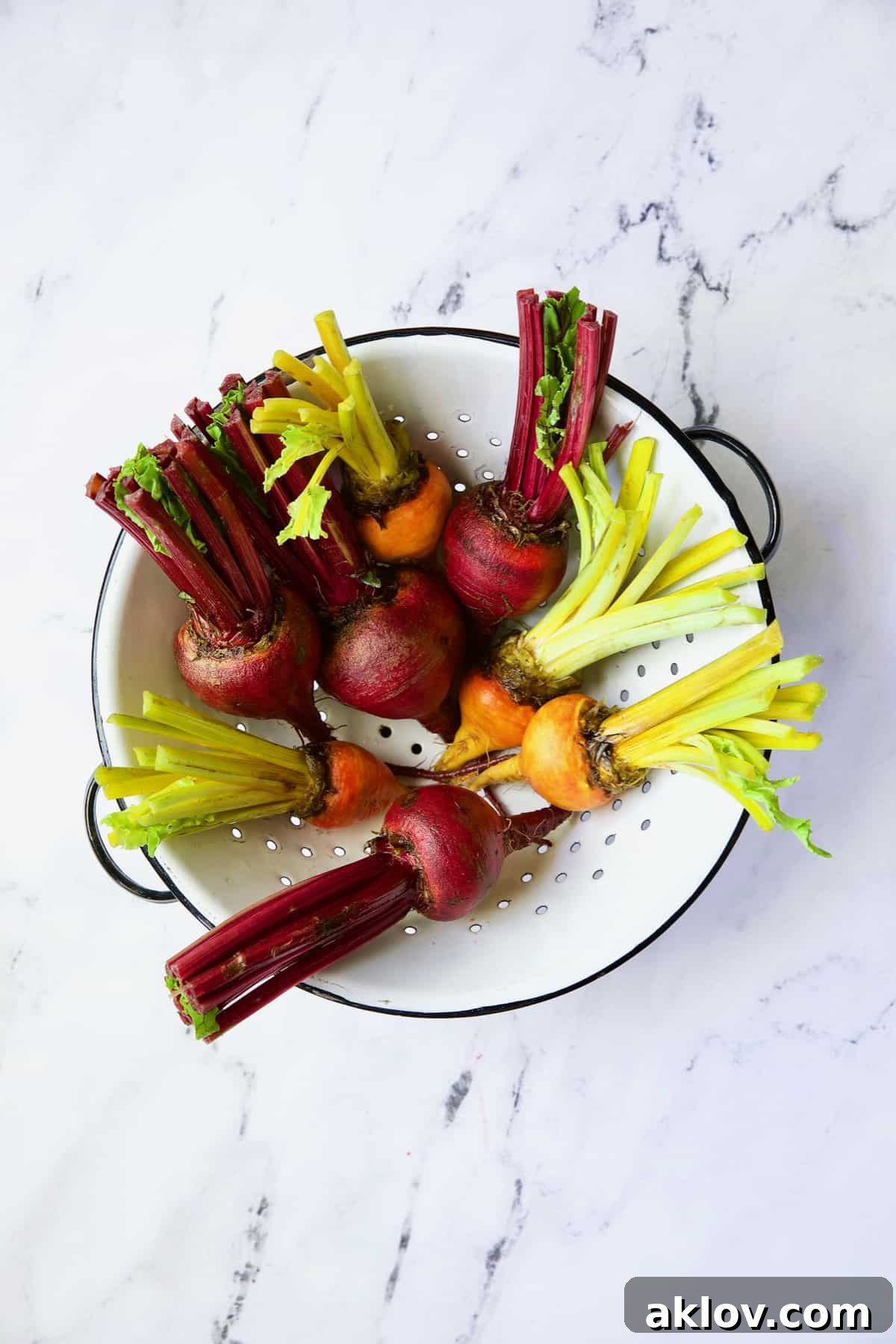 Uncooked red and yellow beets in white colander.
