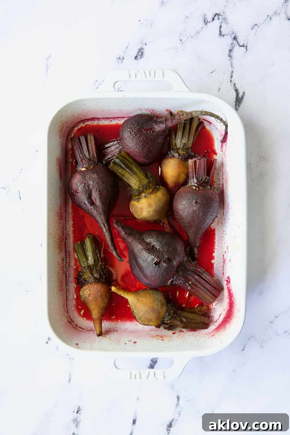 Roasted red and yellow beets in white baking dish.