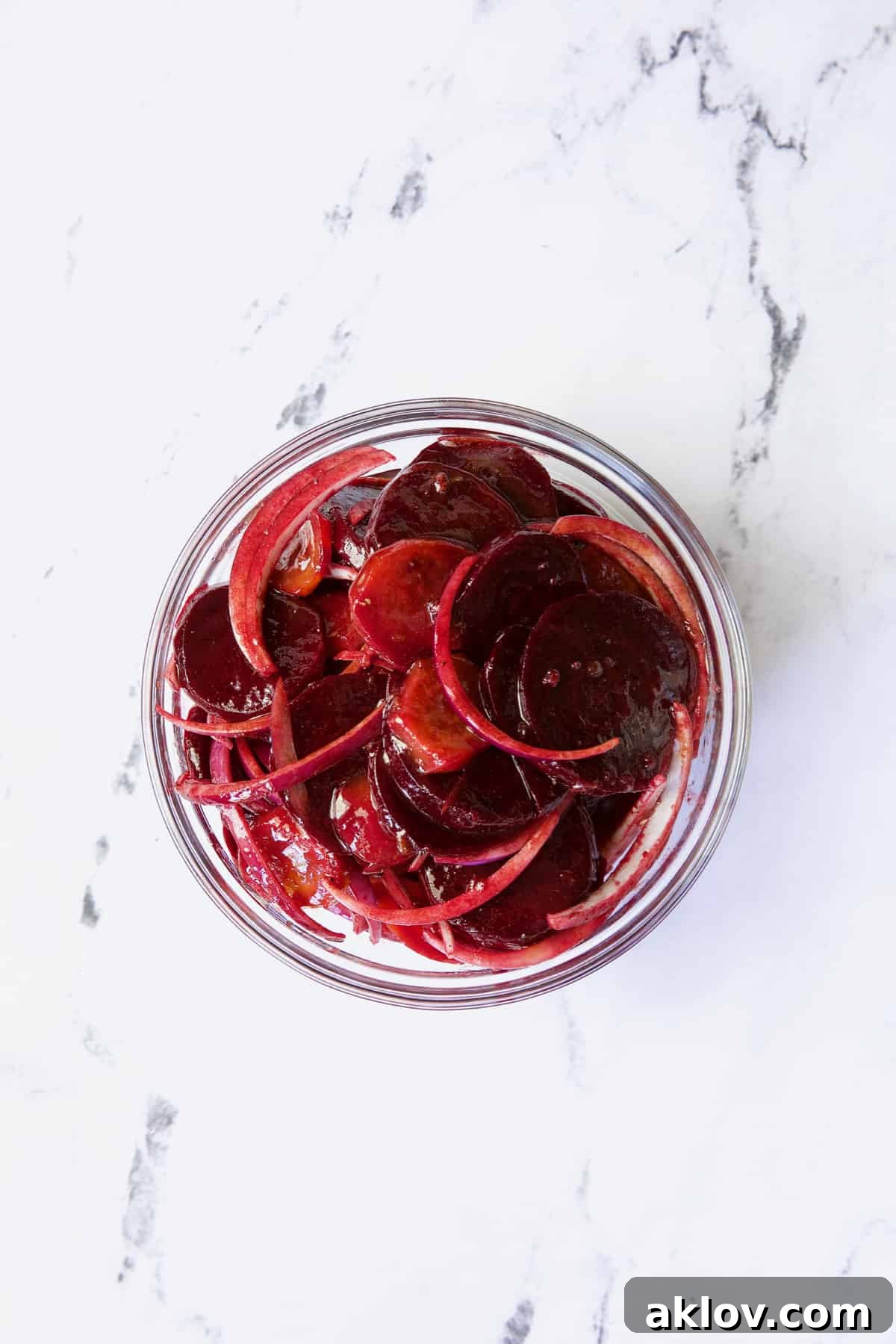 Beets and onions tossed with dressing in glass bowl.