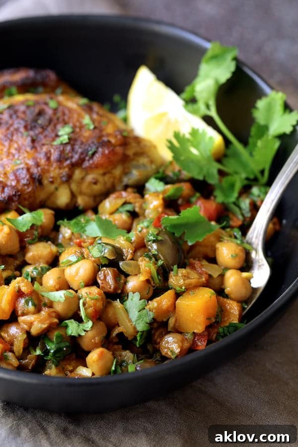 Authentic Moroccan Chicken Tagine 8 A close-up view of the rich and textured butternut squash, chickpea, and olive mixture from the Moroccan Chicken Tagine in a black bowl.