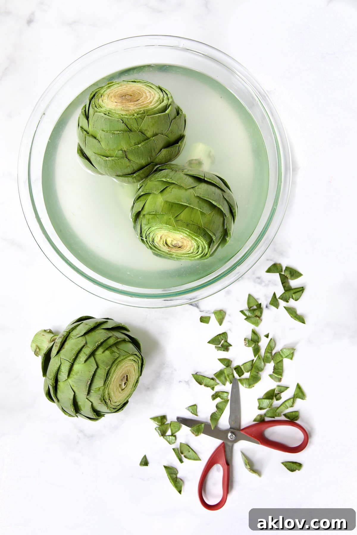 Buttery Garlic Roasted Artichokes 6 Three artichokes being trimmed with two in lemon water.