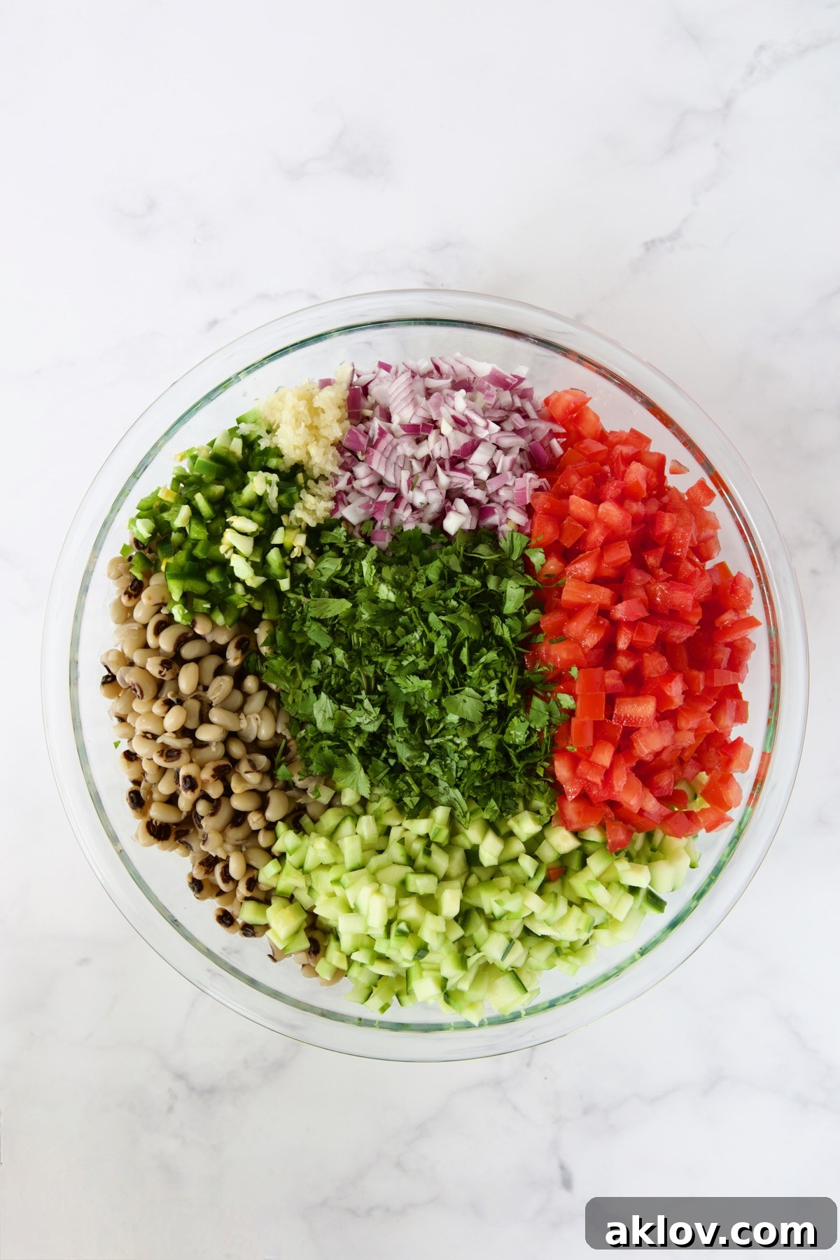 Individual ingredients for Black-Eyed Pea Salad artfully arranged in a glass bowl, awaiting their flavorful combination.