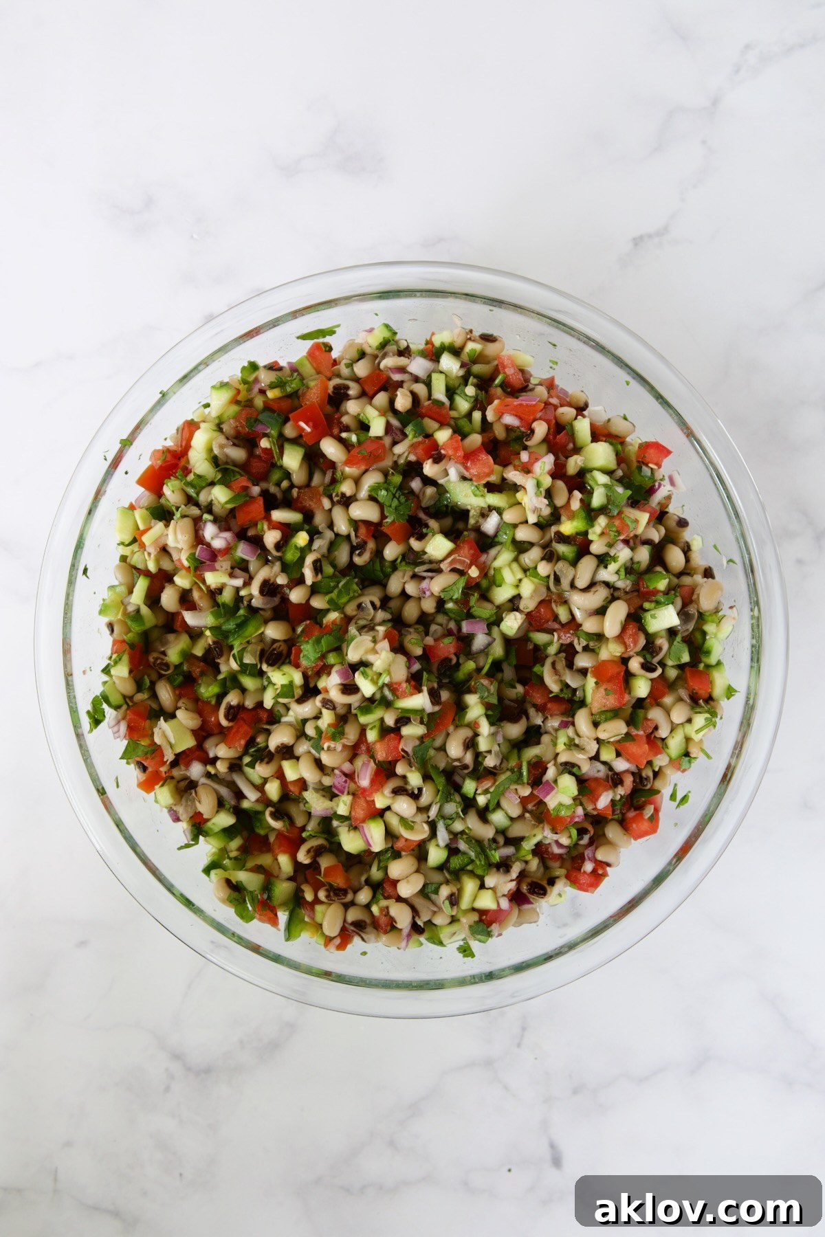 All the delicious ingredients for Black-Eyed Pea Salad expertly combined in a glass bowl, showcasing a harmonious blend of colors and textures.