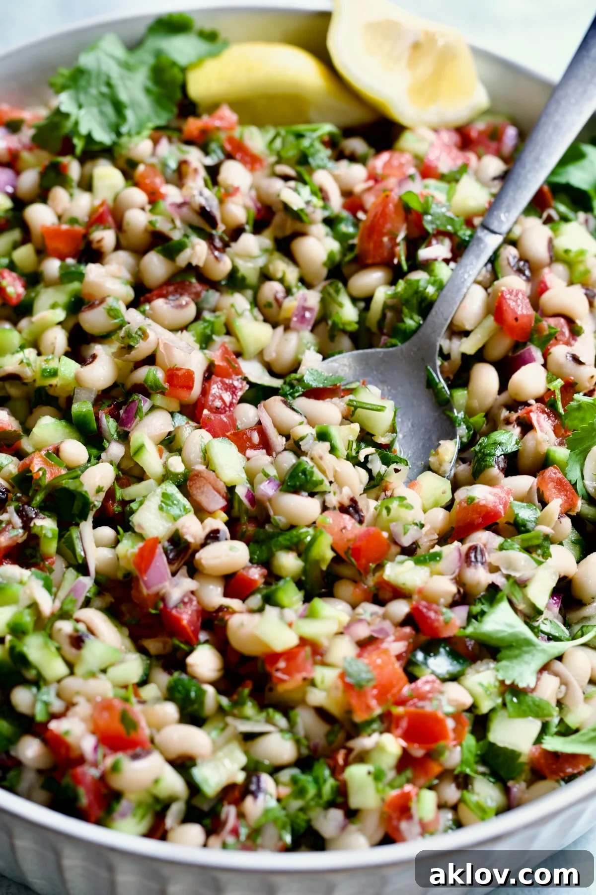 A close-up view of the Spicy Black-Eyed Pea Salad with a serving spoon, highlighting the rich textures and vibrant colors of its fresh ingredients.