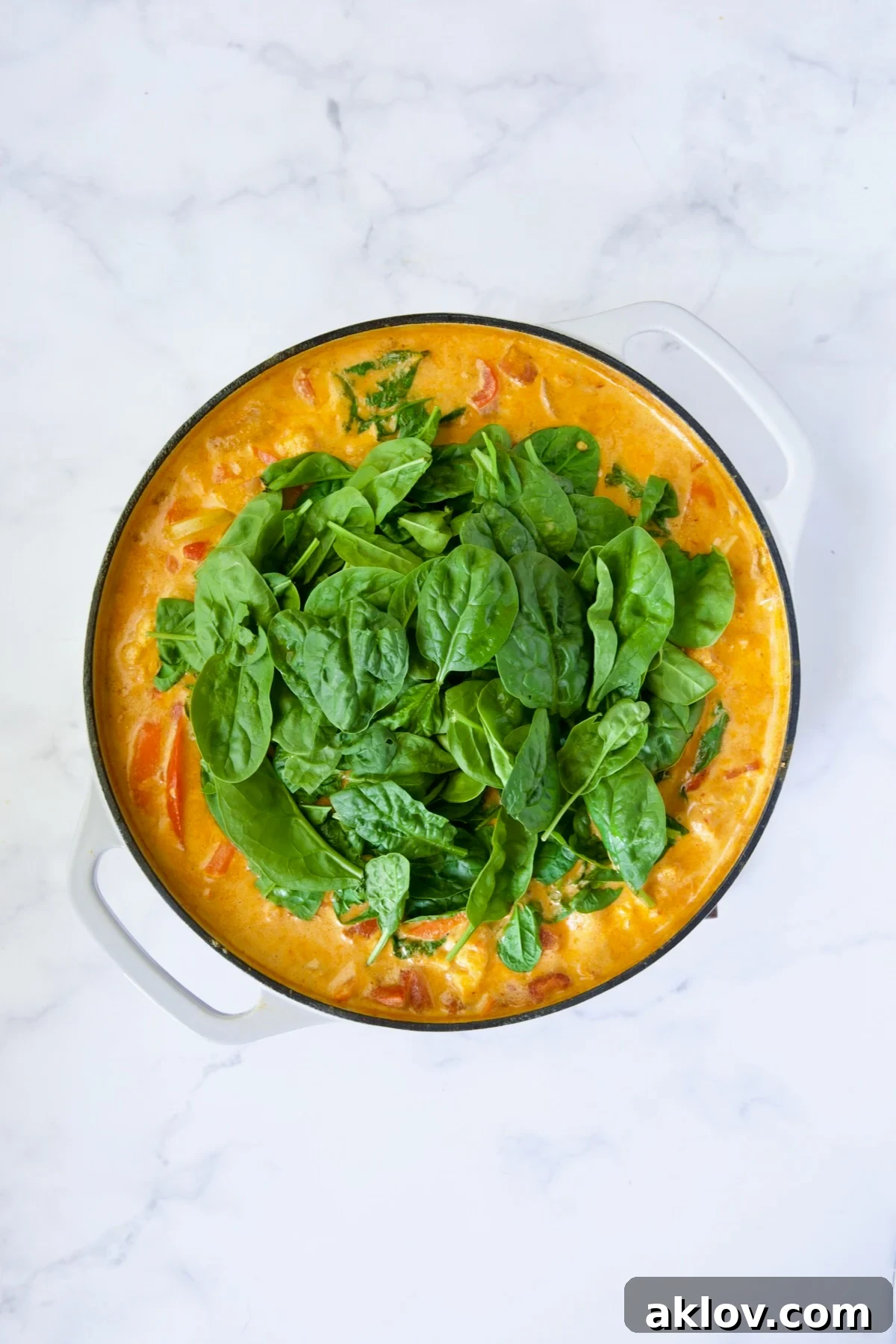 Vegetable curry with baby spinach just added, beginning to wilt into the sauce.