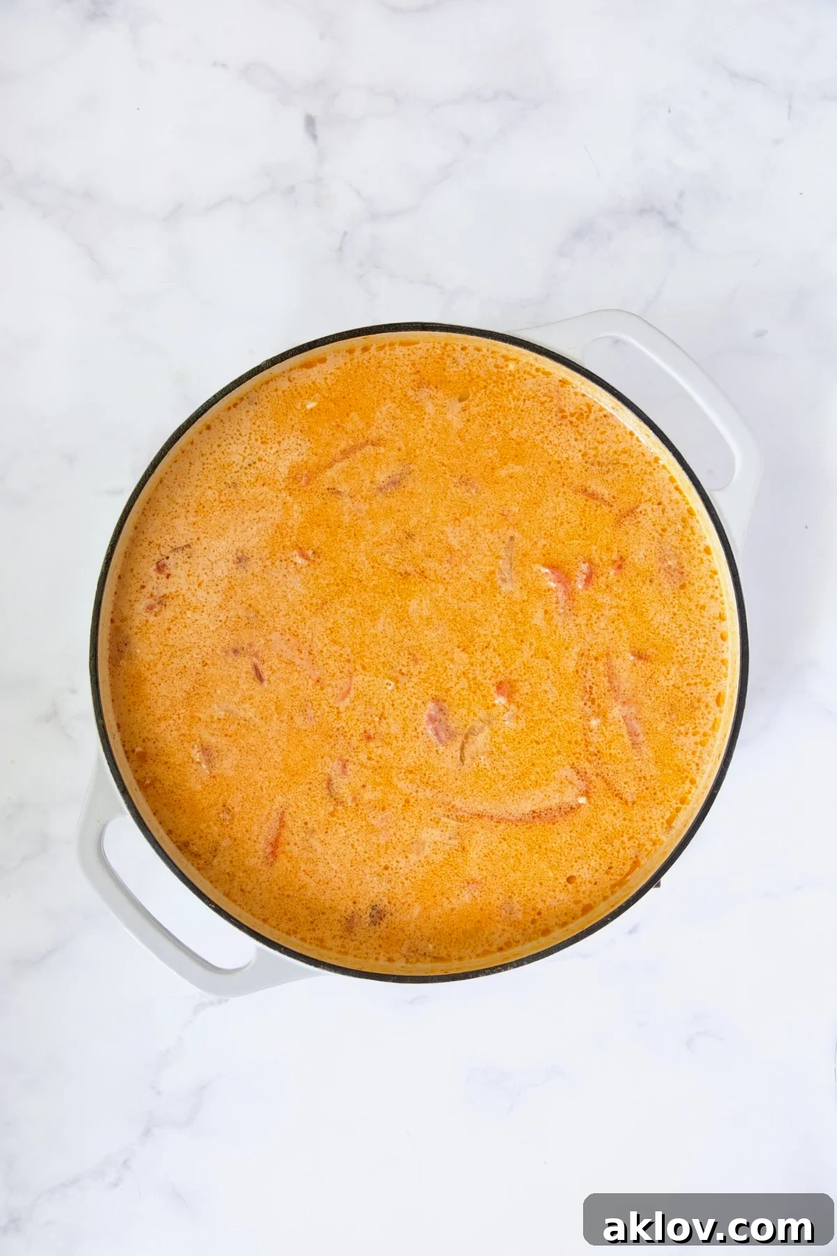 Process shot of the curry base with coconut milk, diced tomatoes, and vegetable broth added, simmering gently.