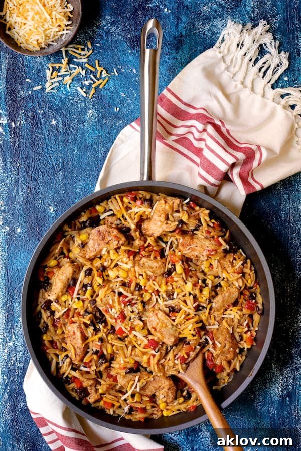 The complete Southwestern Chicken Orzo and Black Bean Skillet dish, elegantly presented on a blue background, accompanied by a festive red and white striped towel.