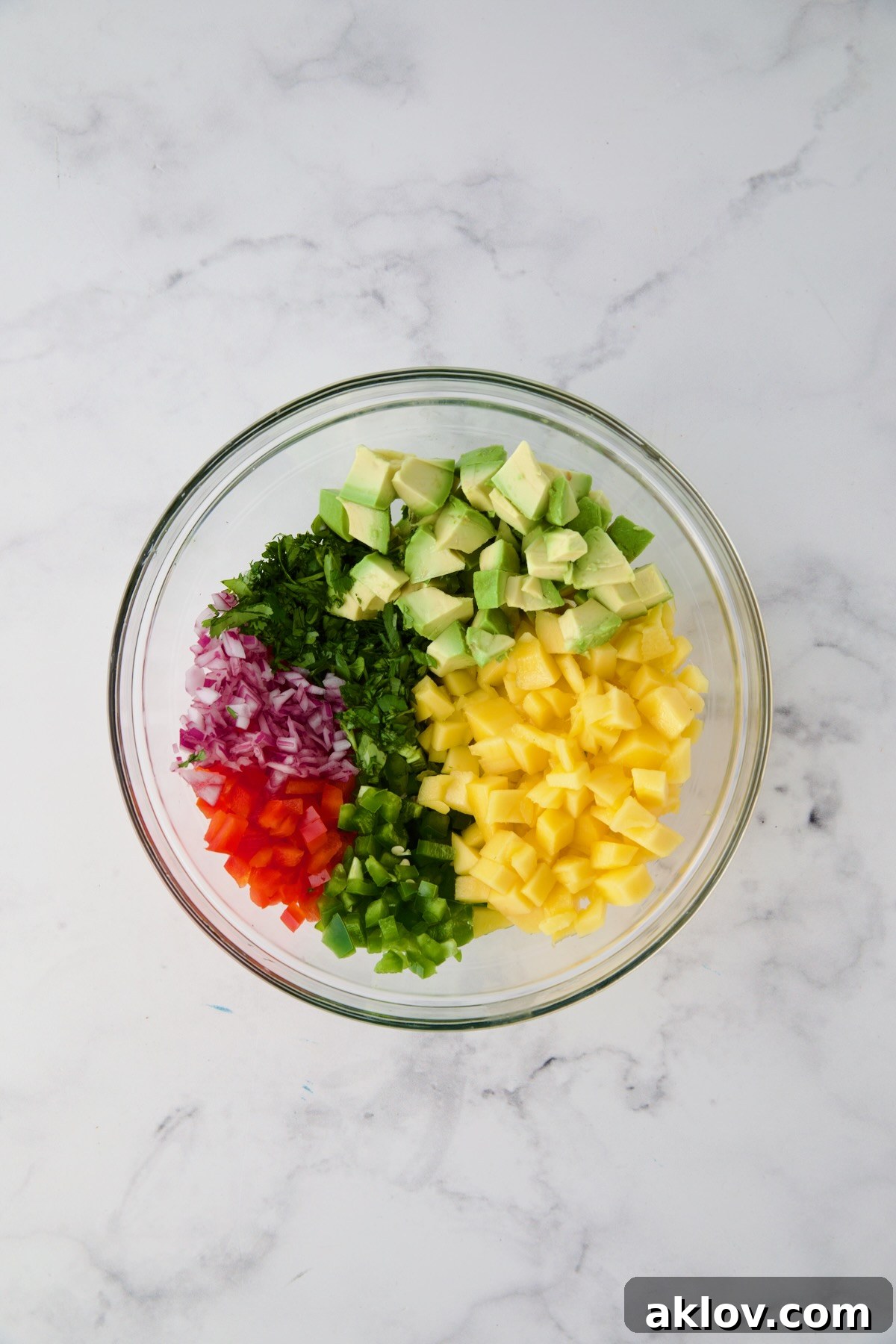 Ingredients for mango and avocado salsa in glass bowl before being stirred together.