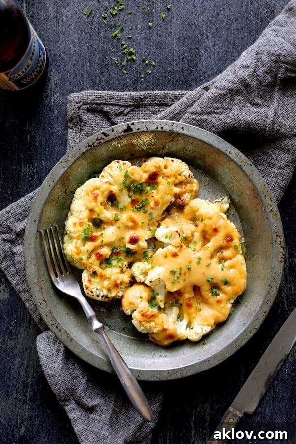 Cauliflower Welsh Rarebit served in a rustic metal dish on a gray napkin, showcasing its golden, bubbling cheese topping.