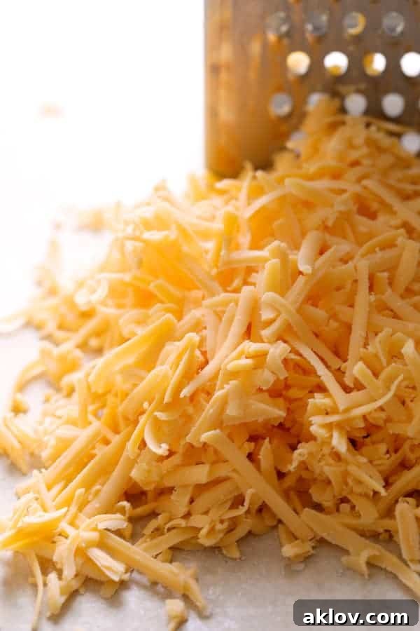 A mound of freshly shredded sharp cheddar cheese, ready for the sauce.