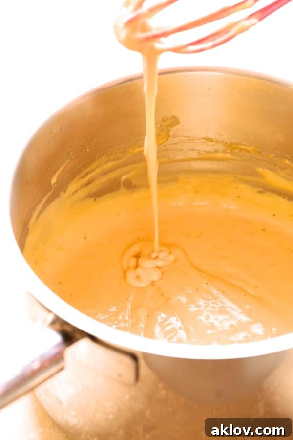 Rich, golden cheese sauce bubbling gently in a saucepan.