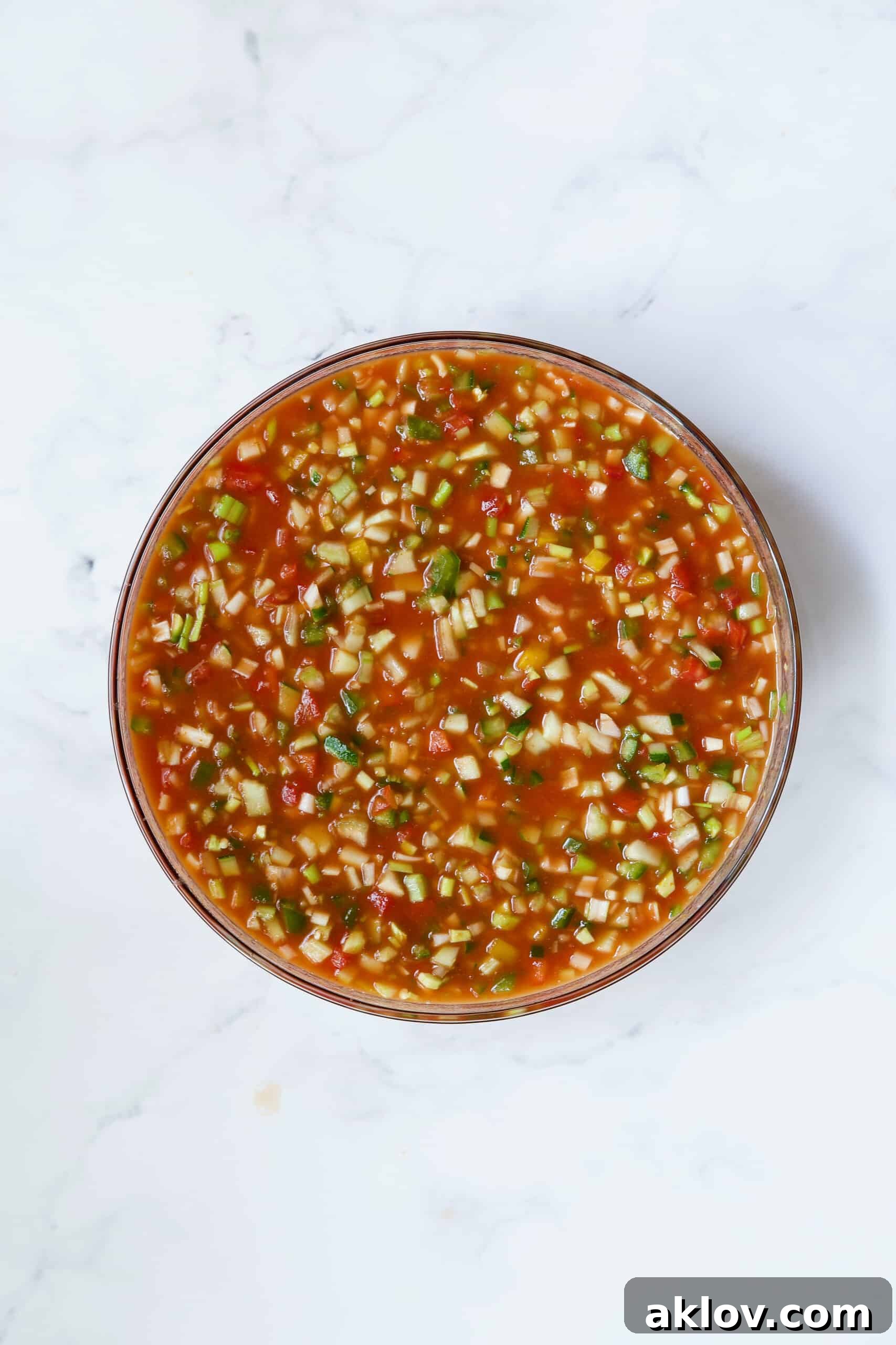 A large glass bowl filled with vibrant Very Veggie Gazpacho, showcasing its chunky texture.