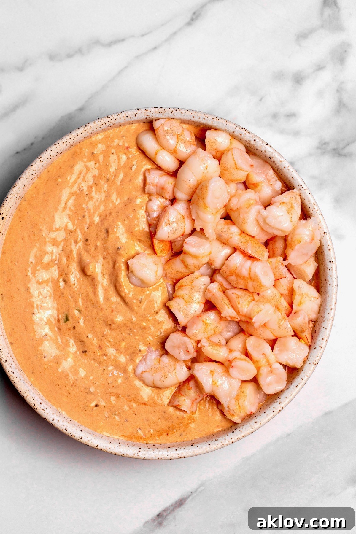 The creamy dip with half of the chopped shrimp stirred in, demonstrating the incorporation process.