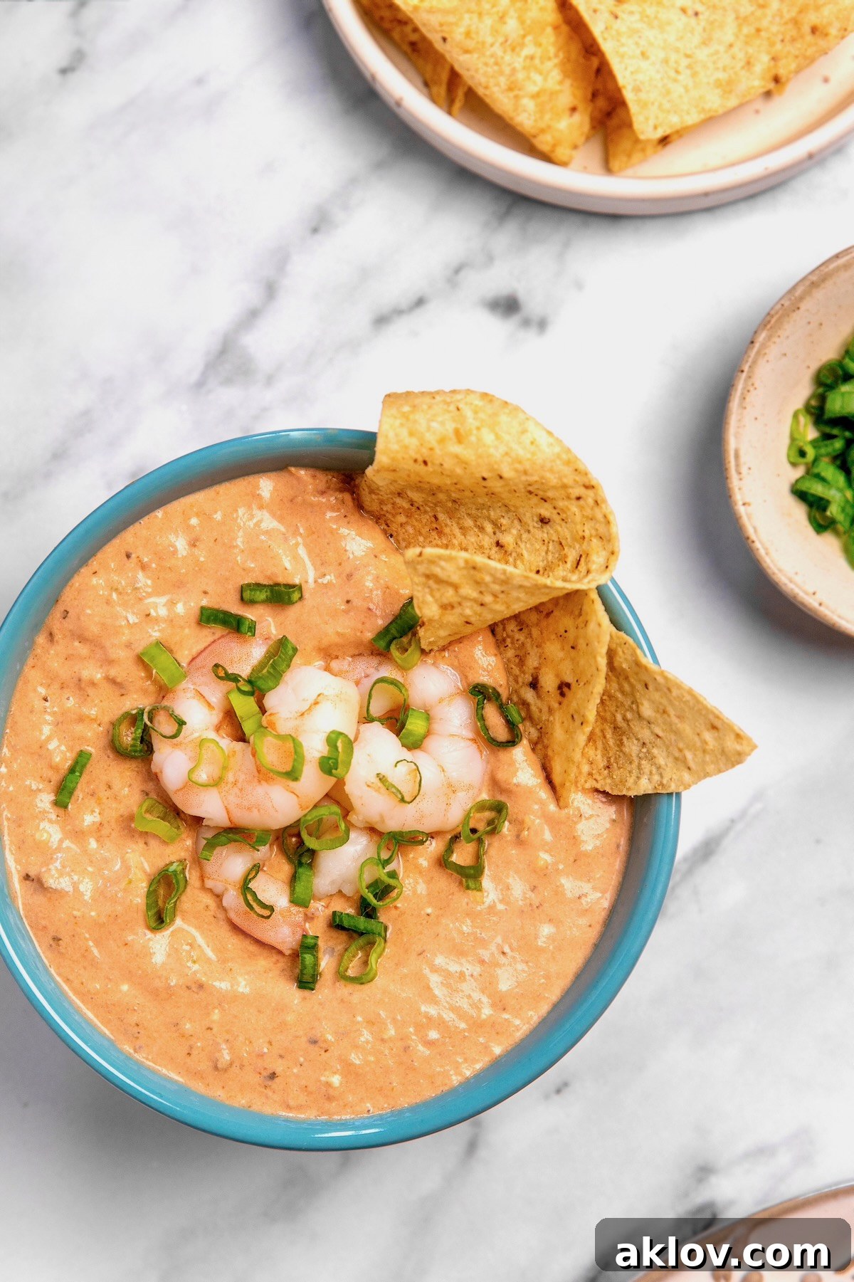 Beautifully presented Creamy Shrimp Salsa Dip in a bright blue bowl, garnished with whole shrimp and scallions, ready to be served with tortilla chips.