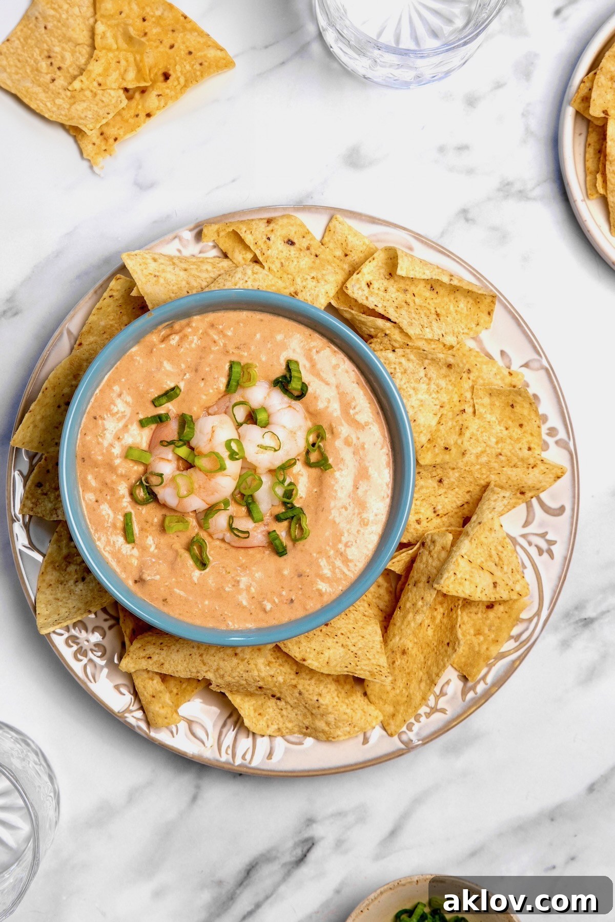 An overhead shot of the Creamy Shrimp Salsa Dip in a bright blue bowl, garnished and ready to be enjoyed with tortilla chips on a large platter.