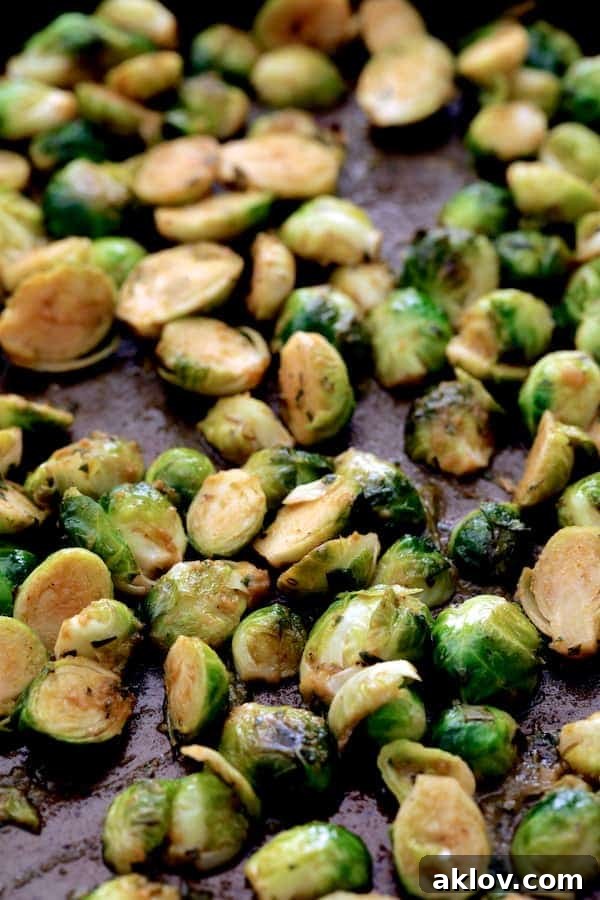 A baking sheet filled with beautifully roasted Brussels sprouts, showing off their golden-brown and slightly charred edges.