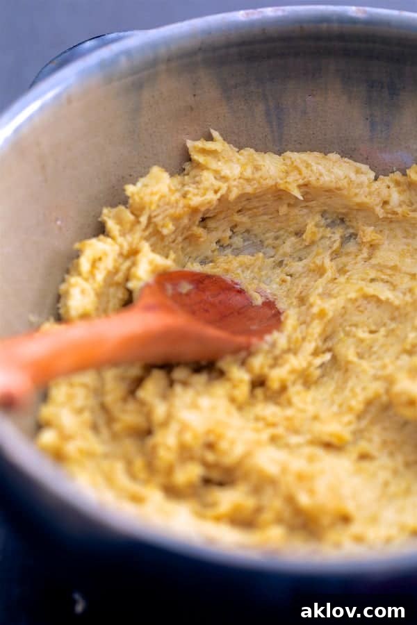 Softened butter being mixed with vibrant green curry paste in a small bowl using a wooden spoon, creating the flavorful Thai green curry butter.