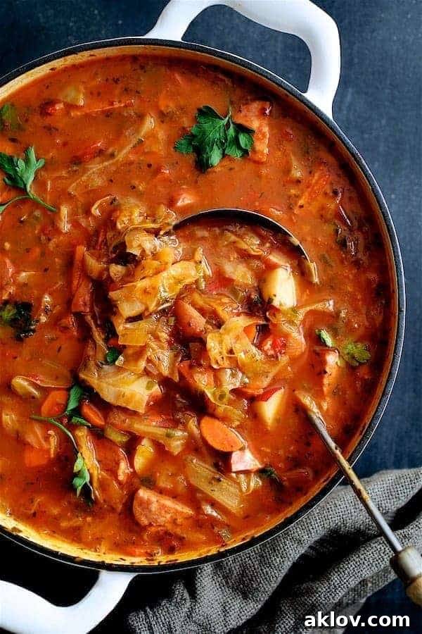 A hearty Old-Fashioned Potato Cabbage and Kielbasa Soup served in a white Dutch oven with a ladle, ready to warm you.
