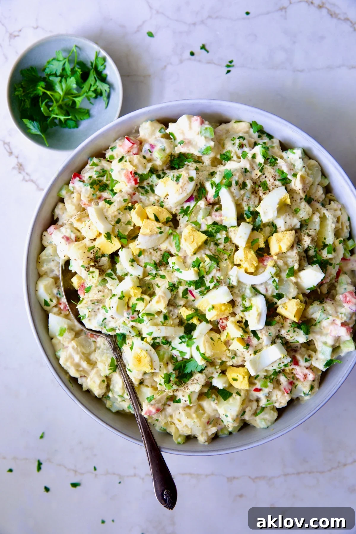 Serving Horseradish Potato Salad from a light blue bowl, showing its creamy texture, vibrant ingredients, and inviting appearance, ready for a delicious meal.