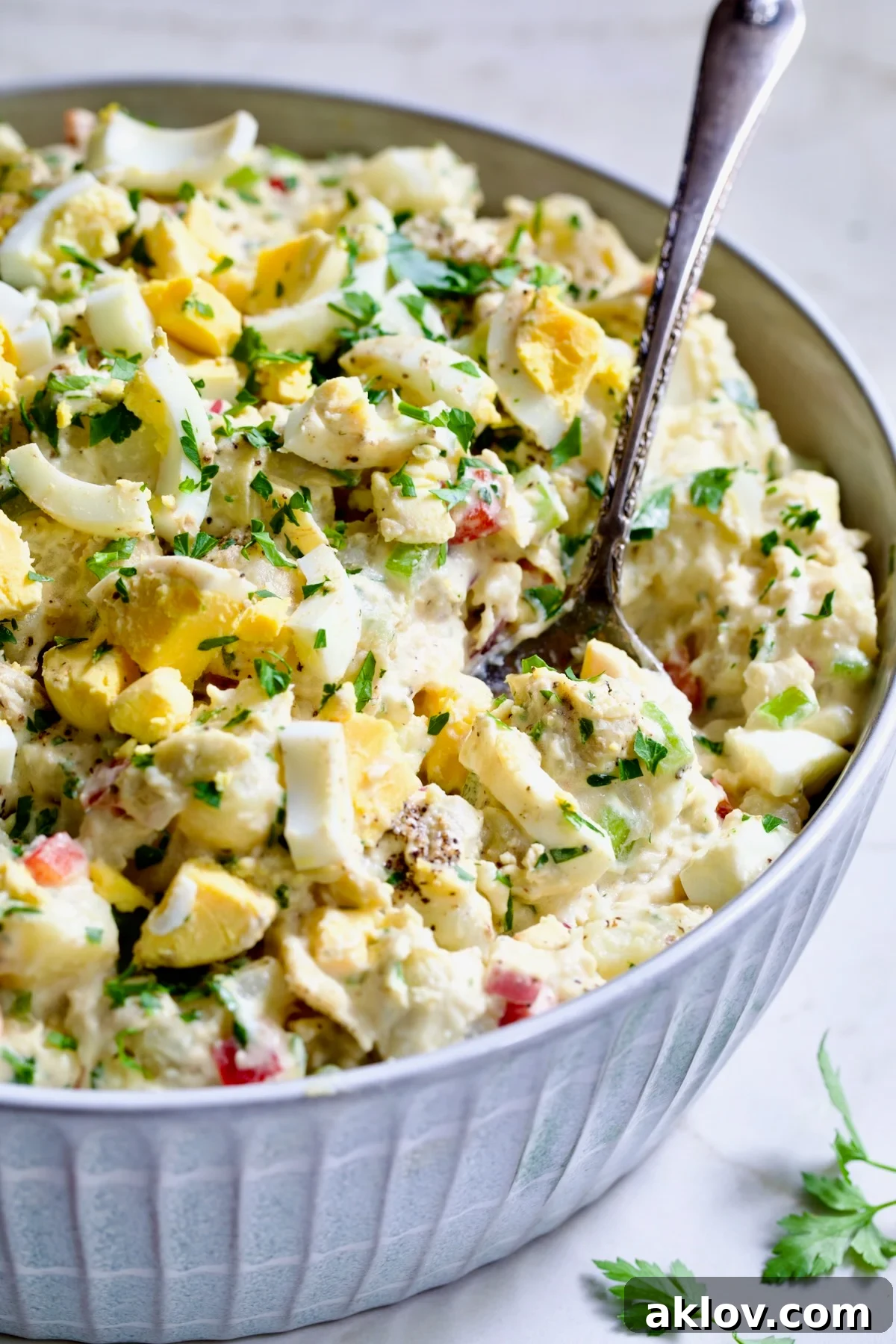 Horseradish Potato Salad elegantly presented in a light blue bowl with a serving spoon, emphasizing its inviting texture and readiness to be savored.