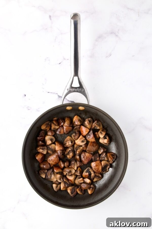 Earthy cremini mushrooms sautéing in a nonstick skillet, achieving a perfect golden brown.