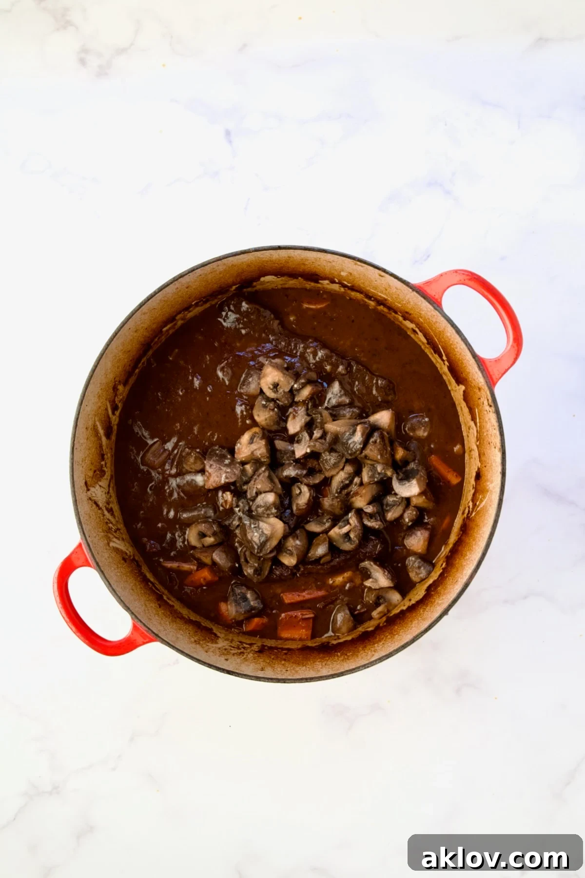 Golden brown sautéed mushrooms incorporated into the Short Ribs Bourguignon in a red Dutch oven.