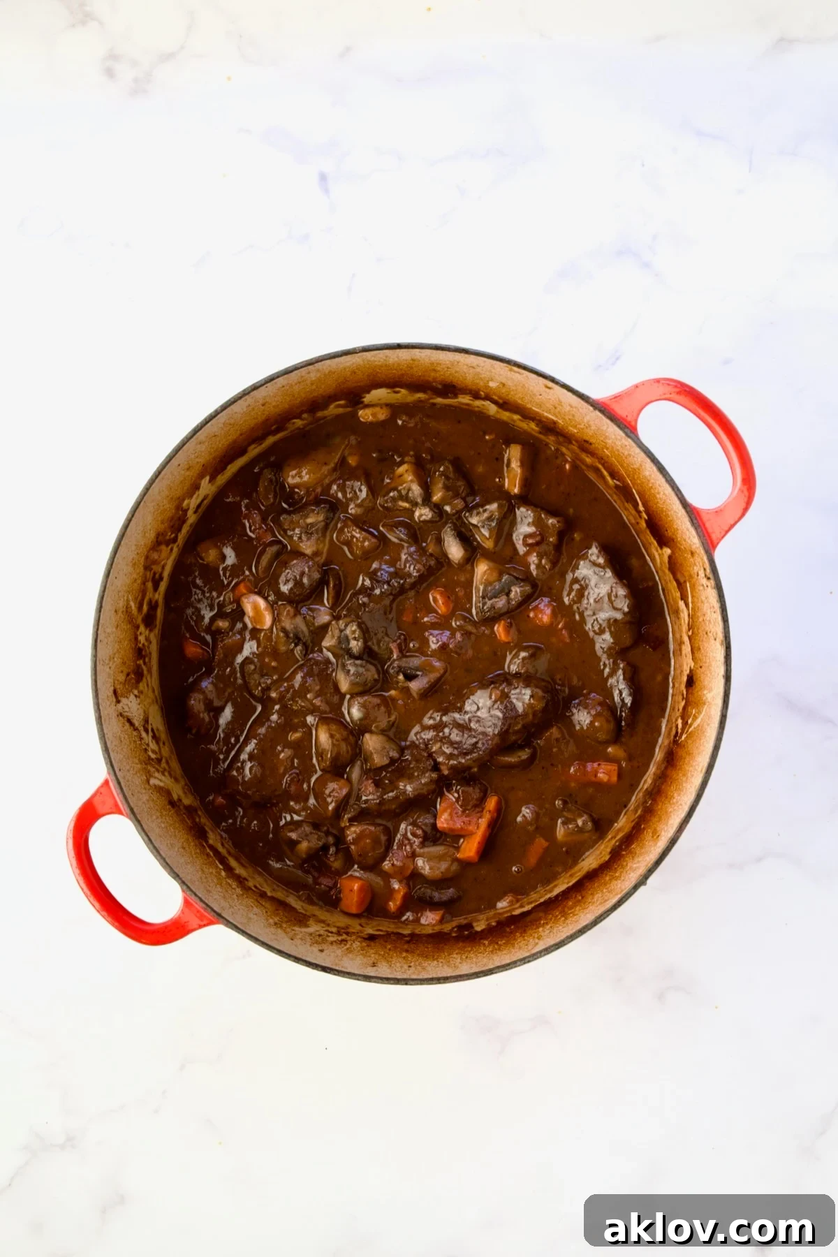 The finished Short Ribs Bourguignon, rich and inviting, prepared in a red Dutch oven.