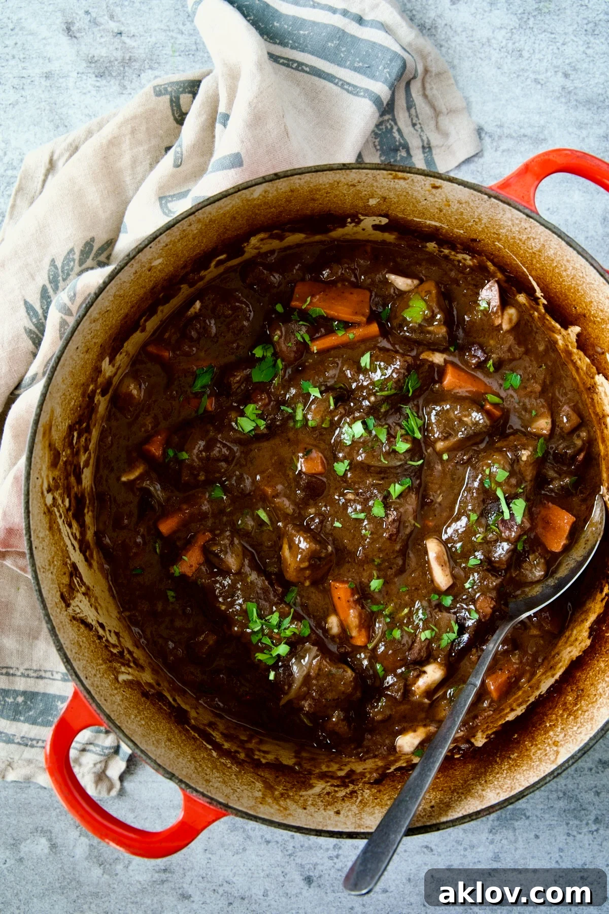 The fully prepared Short Ribs Bourguignon, garnished with fresh parsley, in a red Dutch oven.