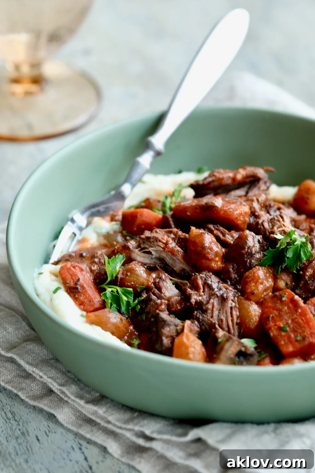 Short Ribs Bourguignon generously served over creamy mashed potatoes in a sage green bowl, a perfect pairing.
