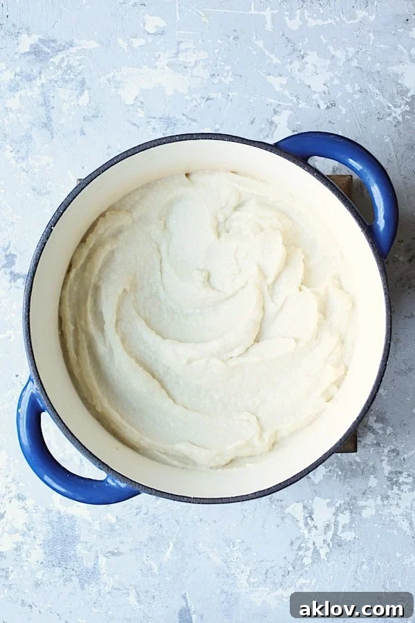 Smooth, pureed cauliflower and white beans in a blue Dutch oven, showcasing the creamy texture achieved after blending.