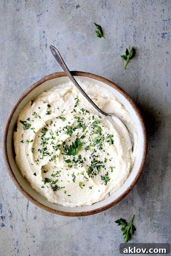 Cauliflower White Bean Puree in earthenware bowl garnished with chopped fresh parsley.
