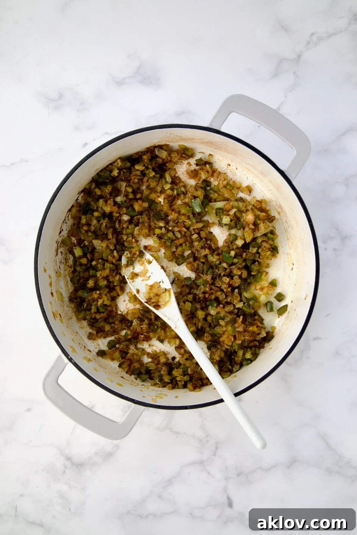 Cooked onions, celery and green bell pepper with Cajun seasoning, cayenne, thyme, garlic and bay leaf added and stirred together.