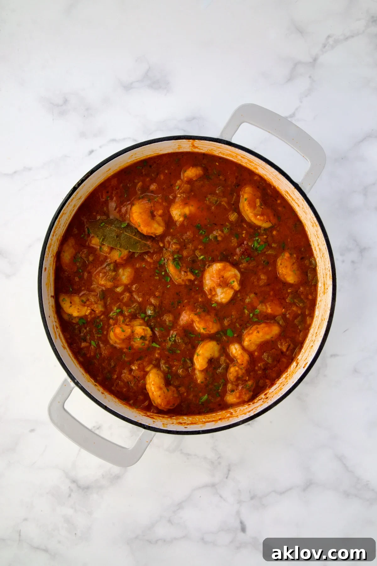 Finished Shrimp Creole with cooked shrimp in white enamel cast iron skillet.