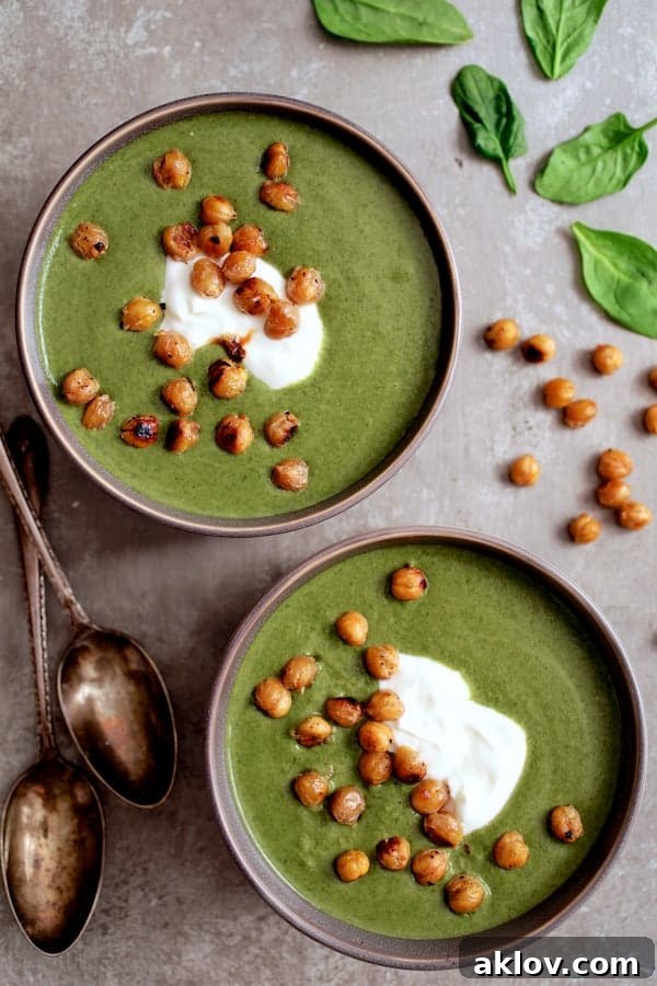 Photo of two beautifully presented bowls of Spinach and Goat Cheese Bisque, topped with crispy lemon chickpeas and a dollop of Greek yogurt.