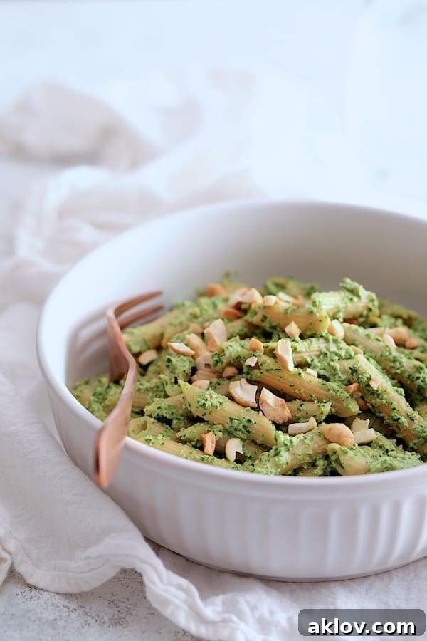 Close-up photo of Penne with Creamy Cashew and Spinach Pesto Sauce in a white bowl, highlighting the creamy texture and fresh garnish.