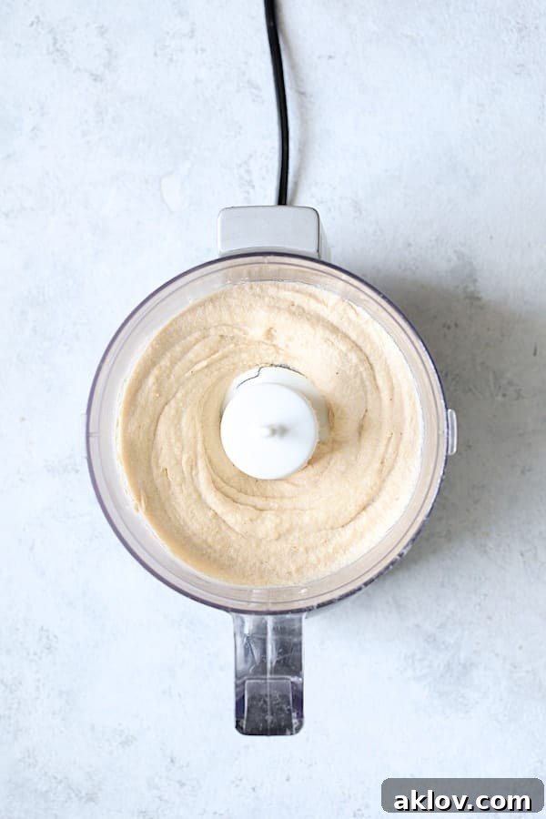 Photo of cashew cream being blended in a food processor, creating a smooth, white mixture.
