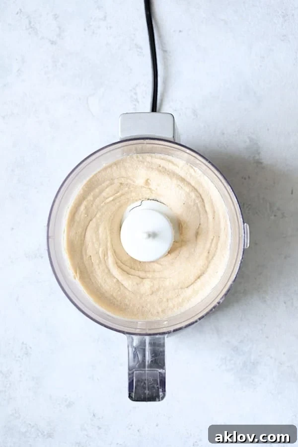 A visual representation of freshly prepared cashew cream, rich and smooth, captured within the confines of a food processor bowl, ready to be incorporated into the next culinary creation.