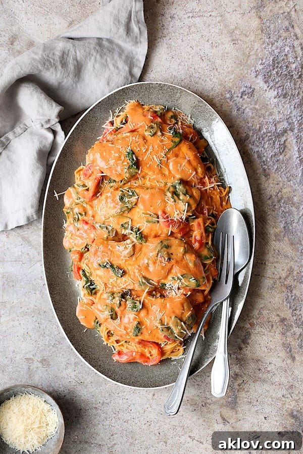 Photo of Chicken in Rosa Sauce with Roasted Red Bell Pepper and Spinach over angel hair pasta on gray-rimmed oval platter.