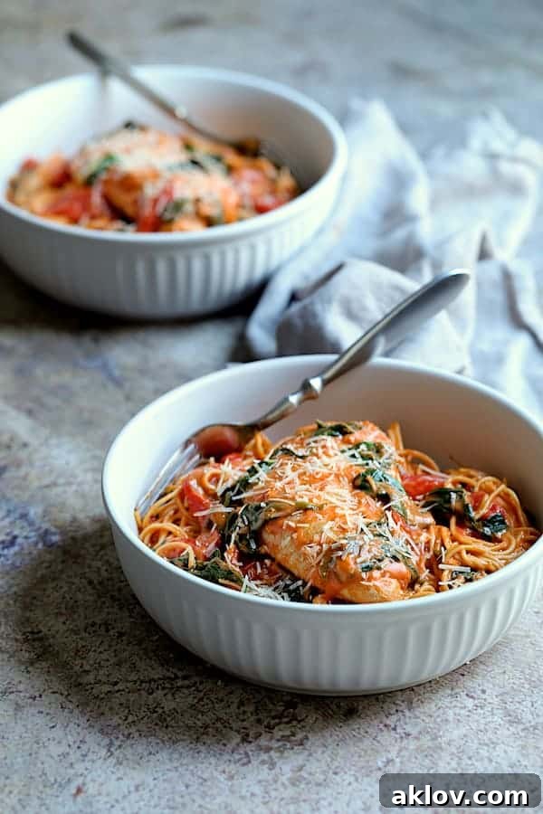 Photo of two servings of Chicken in Rosa Sauce with Roasted Red Bell Pepper and Spinach on gray background.