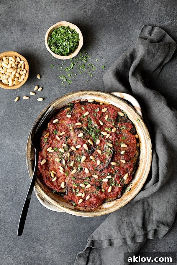 Photo of Turkish Eggplant Casserole - Imam Bayildi on gray background with gray towel. A stunning Turkish Eggplant Casserole (Imam Bayildi) sits proudly on a gray background, accompanied by a matching gray towel, exuding warmth and culinary excellence.