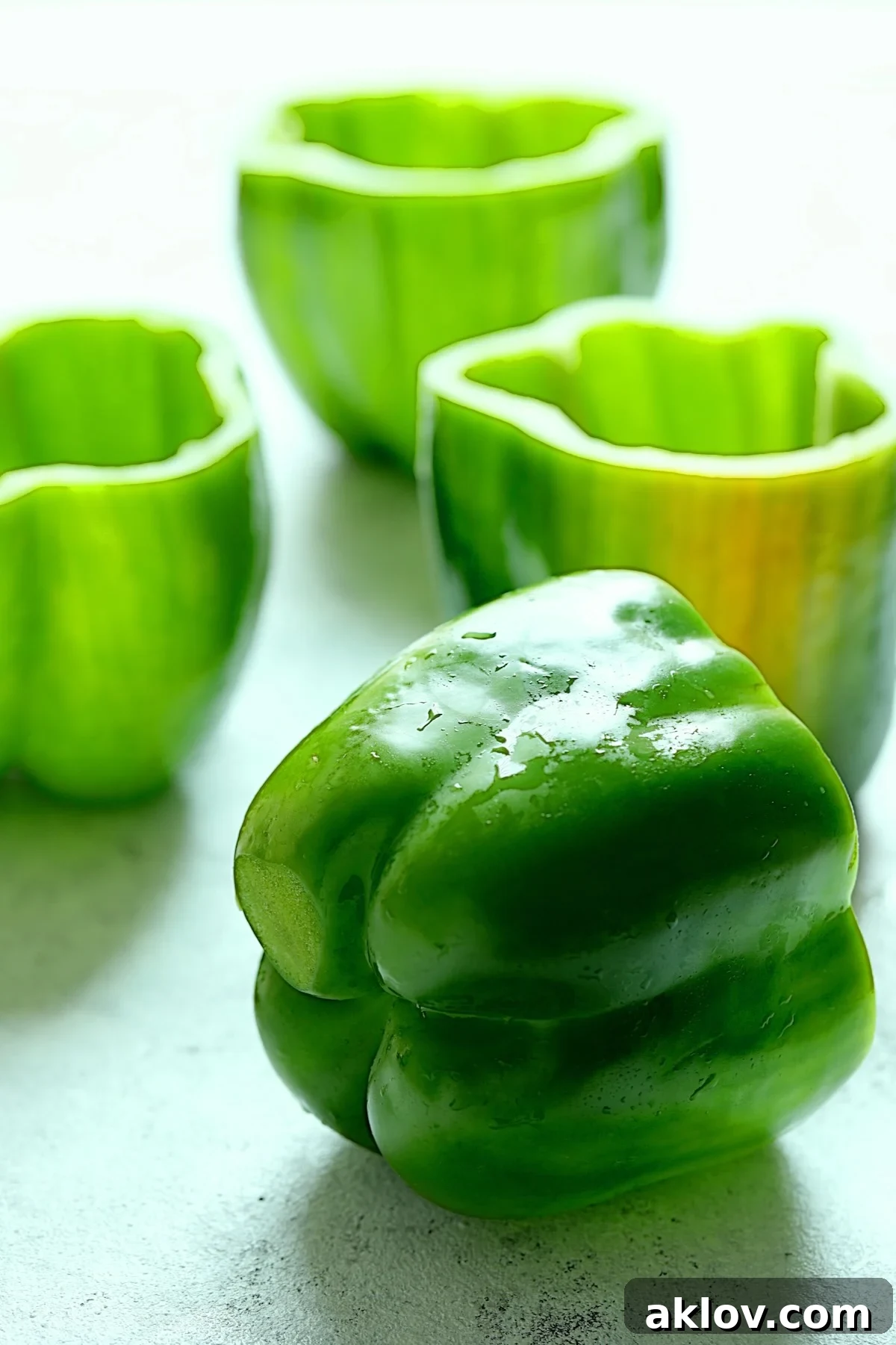 Four green bell peppers with tops removed and ready for pre-baking.
