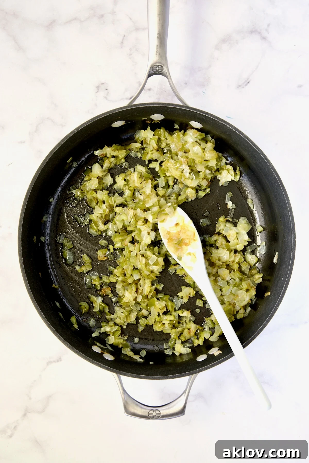 Cooked onions, bell pepper, and celery in a nonstick skillet being stirred.
