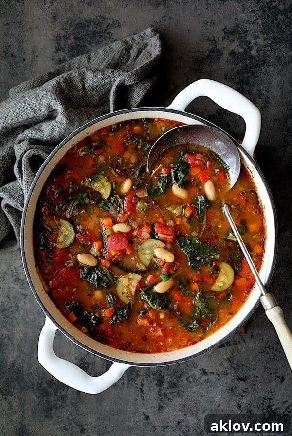 Smoky Spanish Vegetable and White Bean Soup with Kale in white Dutch oven.