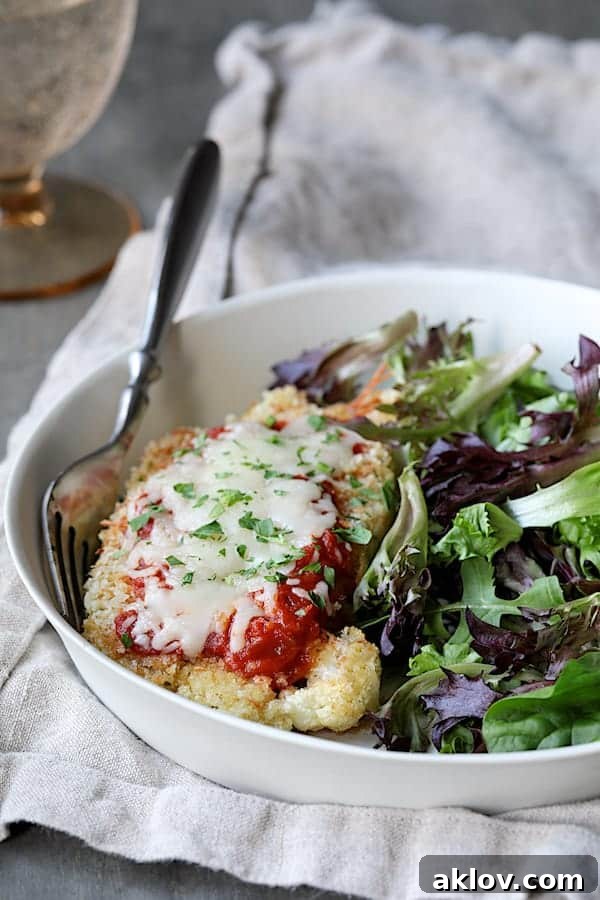 Photo of Cauliflower Parmigiana on white plate with greens.
