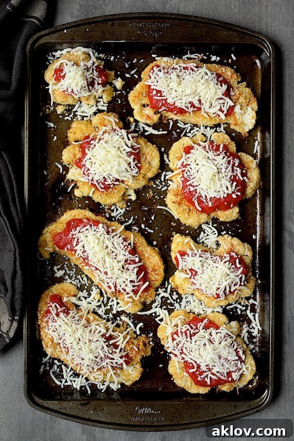 Photo of breaded and baked cauliflower steaks with sauce and sprinkled with cheese.